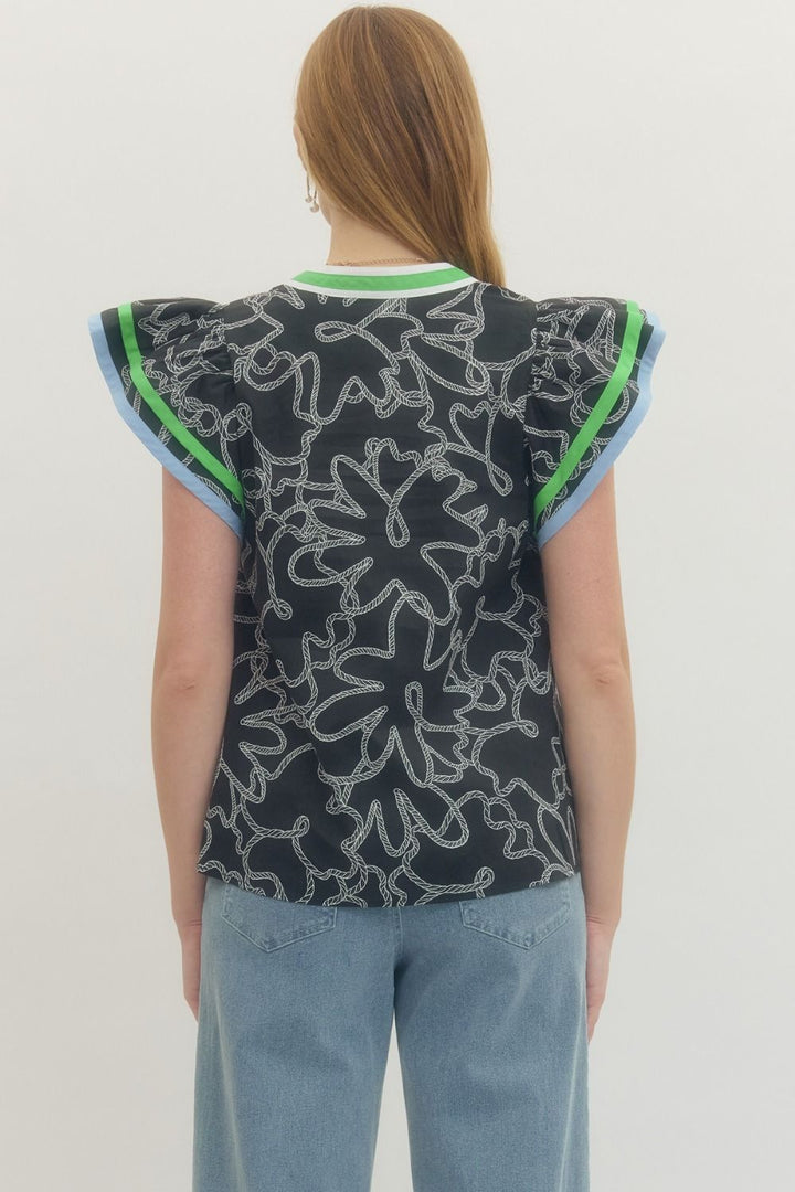 Person wearing a sleeveless top with a floral pattern on a plain background