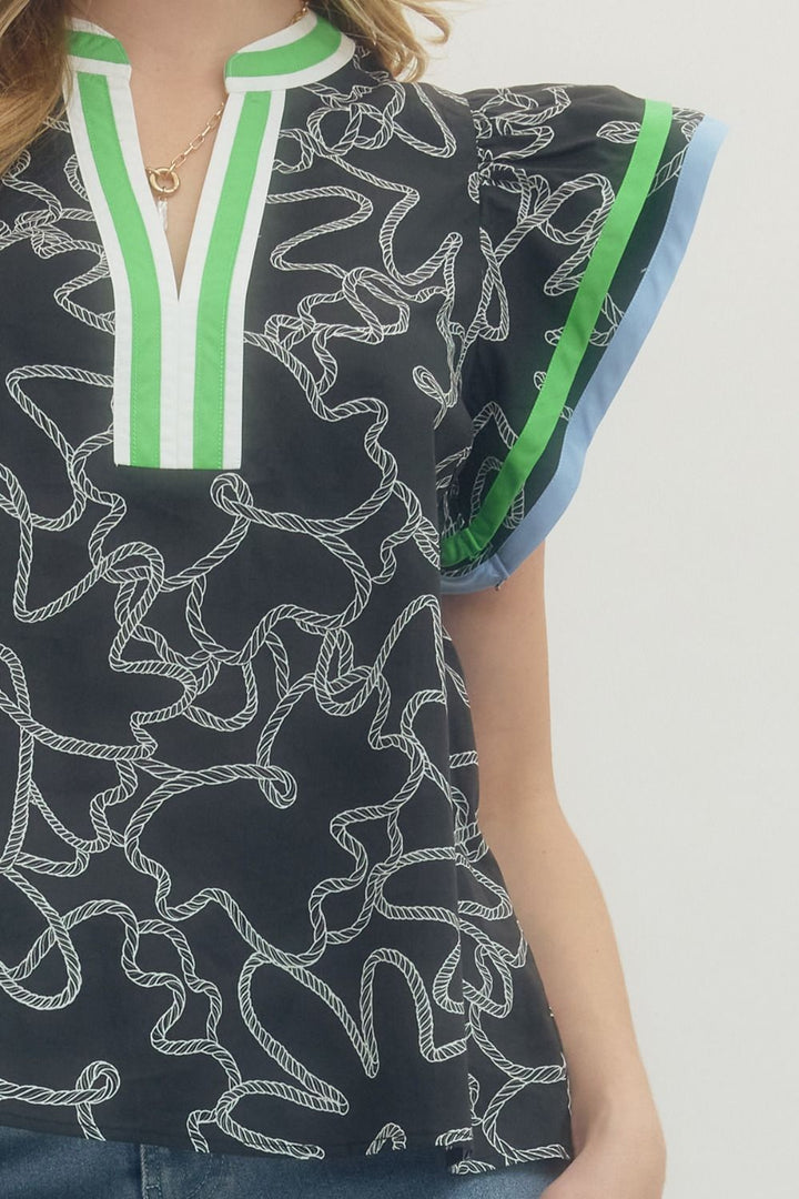 Black patterned top with green and white trim worn by a person on a plain background