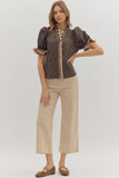 Woman wearing a patterned blouse and beige pants on a white background