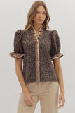 Woman wearing a leopard print blouse with ruffled details on a plain background