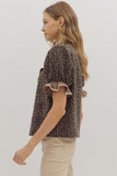 Woman wearing a leopard print top with ruffled sleeves on a plain background