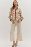 Woman wearing a floral blouse and beige pants on a white background
