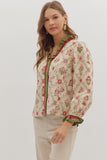 Woman wearing a floral blouse with green trim on a white background