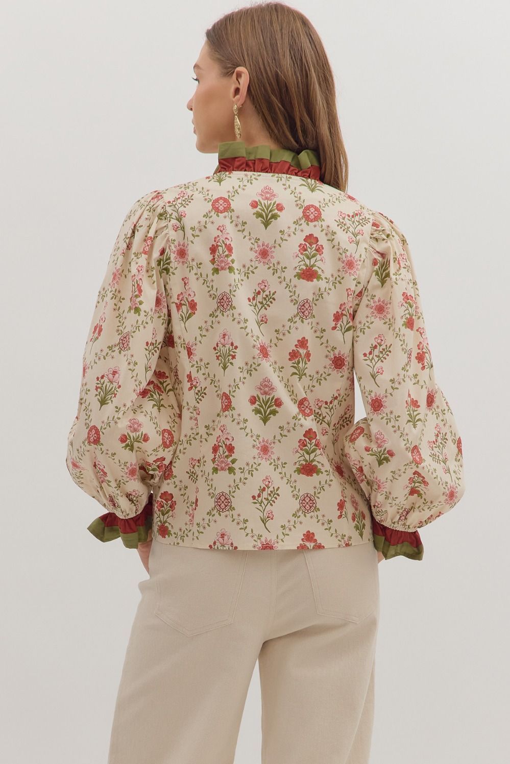 Woman wearing a floral blouse with long sleeves on a plain background