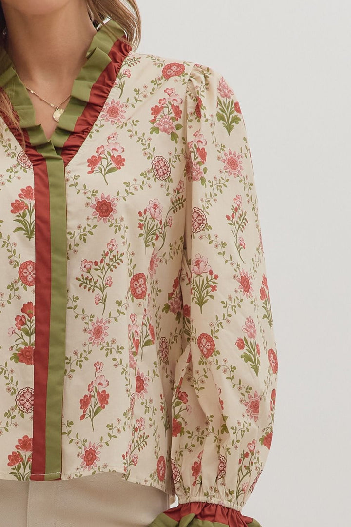 Floral patterned blouse with green and red accents on a plain background