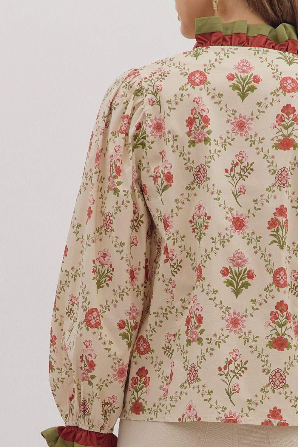 Floral patterned blouse with long sleeves on a plain background