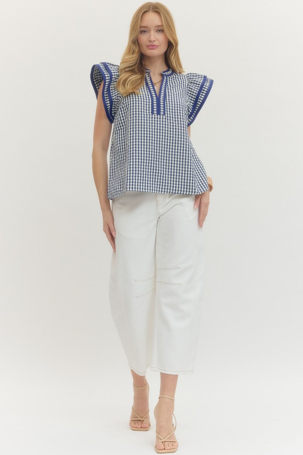 Woman wearing a blue and white checkered blouse with ruffled sleeves on a white background