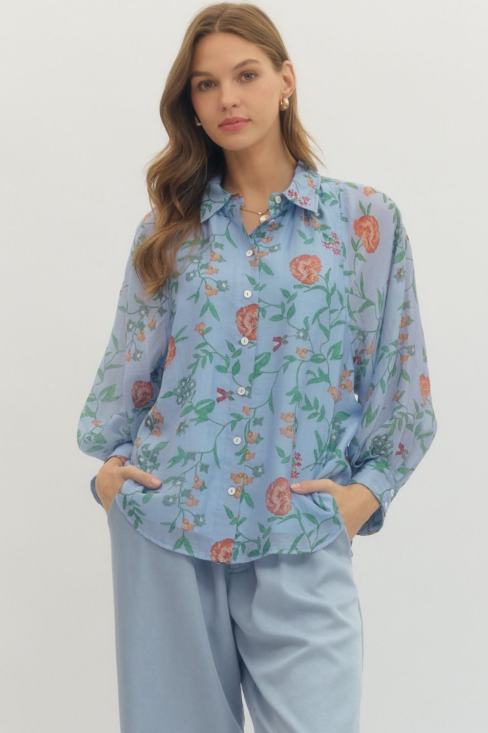 Woman wearing a light blue floral blouse and pants on a white background