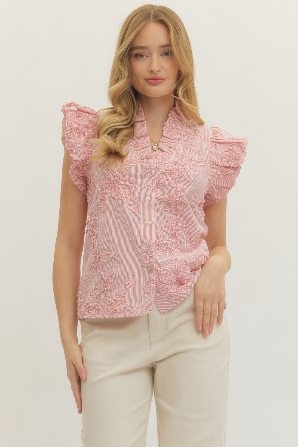 Woman wearing a pink lace top with ruffled sleeves on a white background