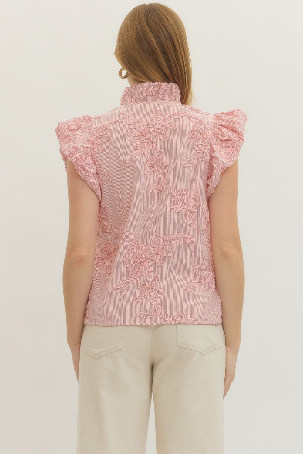 Person wearing a pink embroidered sleeveless top on a plain background