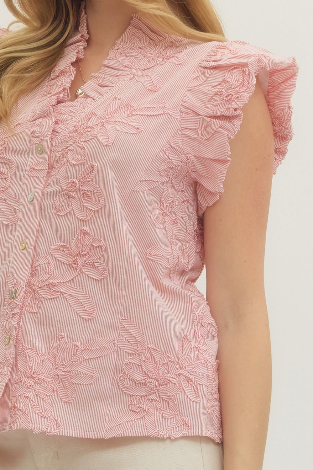 Close-up of a pink blouse with floral embroidery on a white background