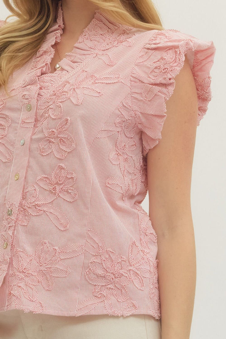 Close-up of a pink blouse with floral embroidery on a white background