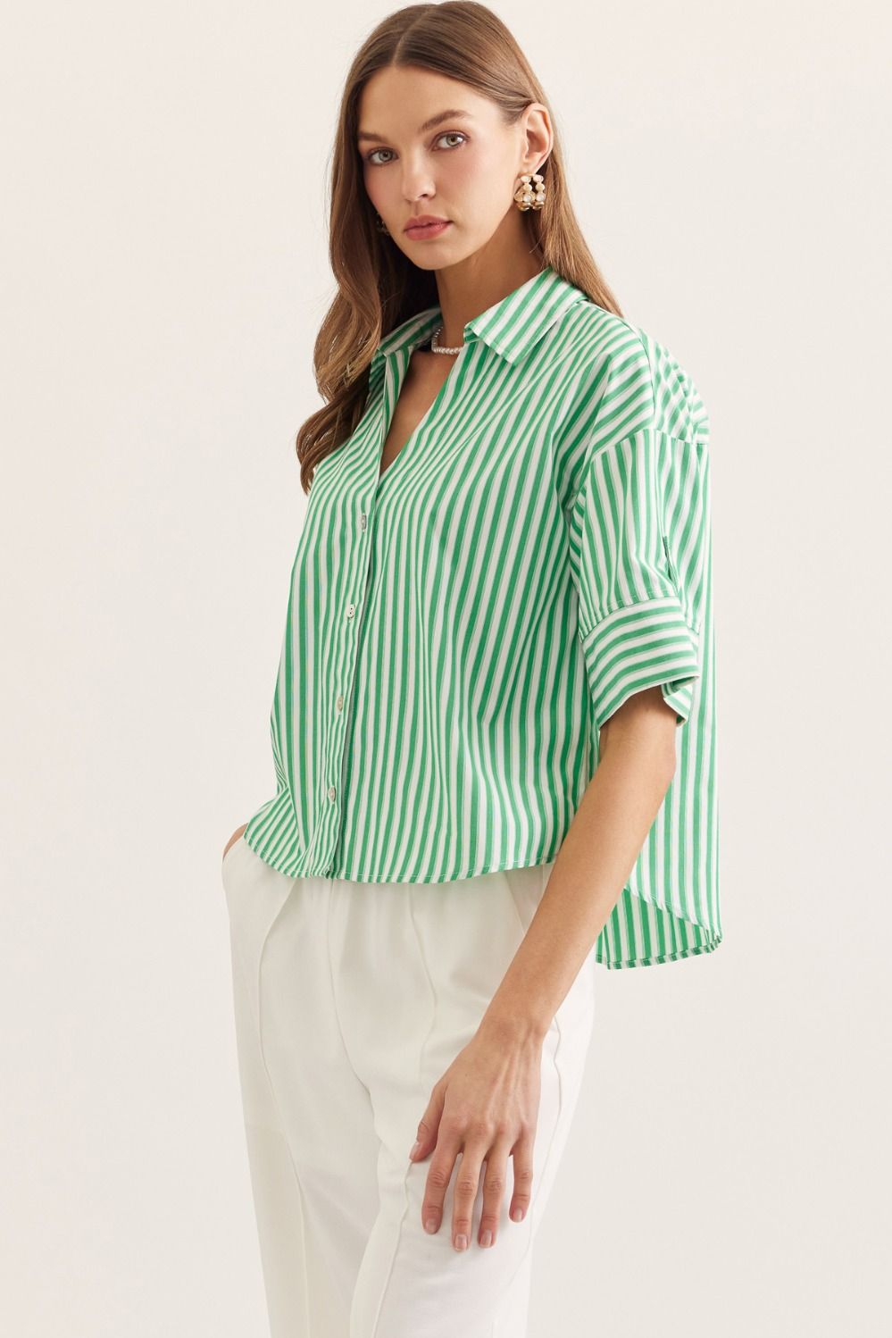 Woman wearing a green and white striped shirt on a plain background