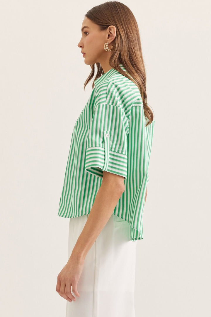 Woman wearing a green and white striped shirt against a plain background