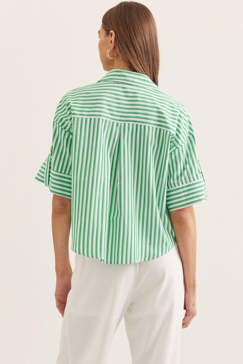 Person wearing a green and white striped shirt on a plain background