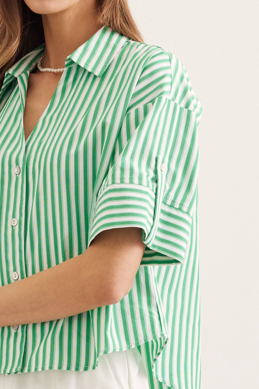Green and white striped shirt worn by a person on a light background