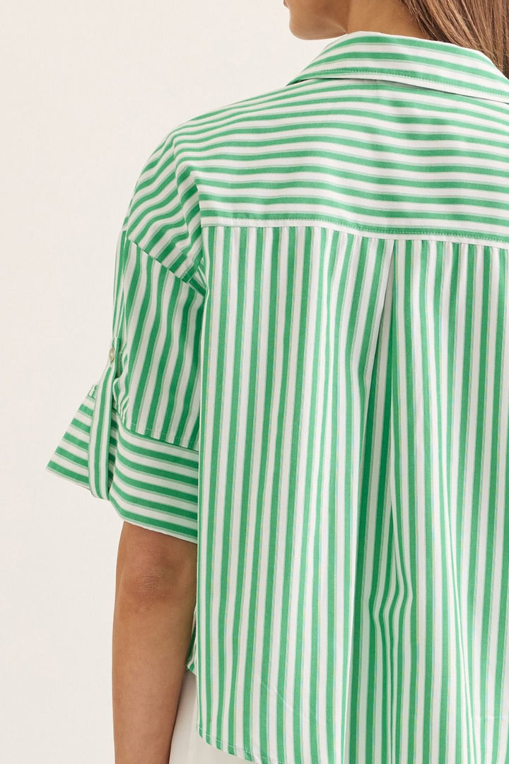Green and white striped shirt worn by a person on a light background