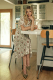 Woman in a floral dress sitting at a kitchen counter.