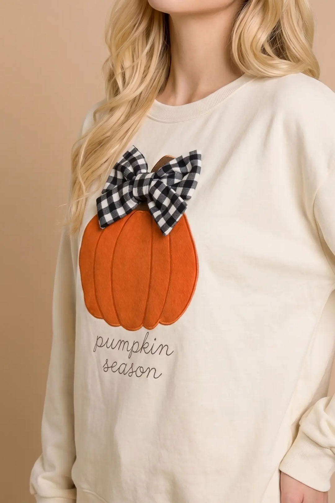 Beige sweatshirt with a pumpkin design and plaid bow on a beige background