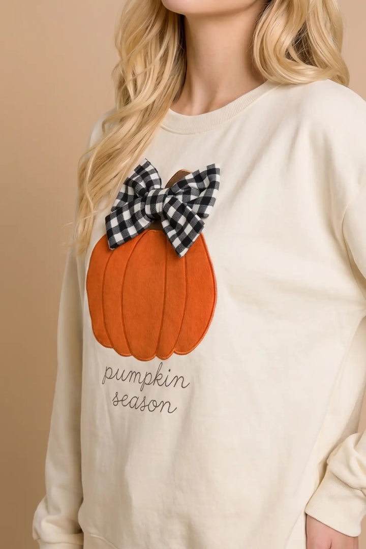 Beige sweatshirt with a pumpkin design and plaid bow on a beige background