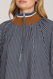 Close-up of a person wearing a striped shirt with a brown collar and zipper.