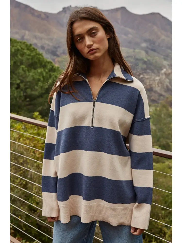 Woman wearing a blue and beige striped sweater with mountains in the background