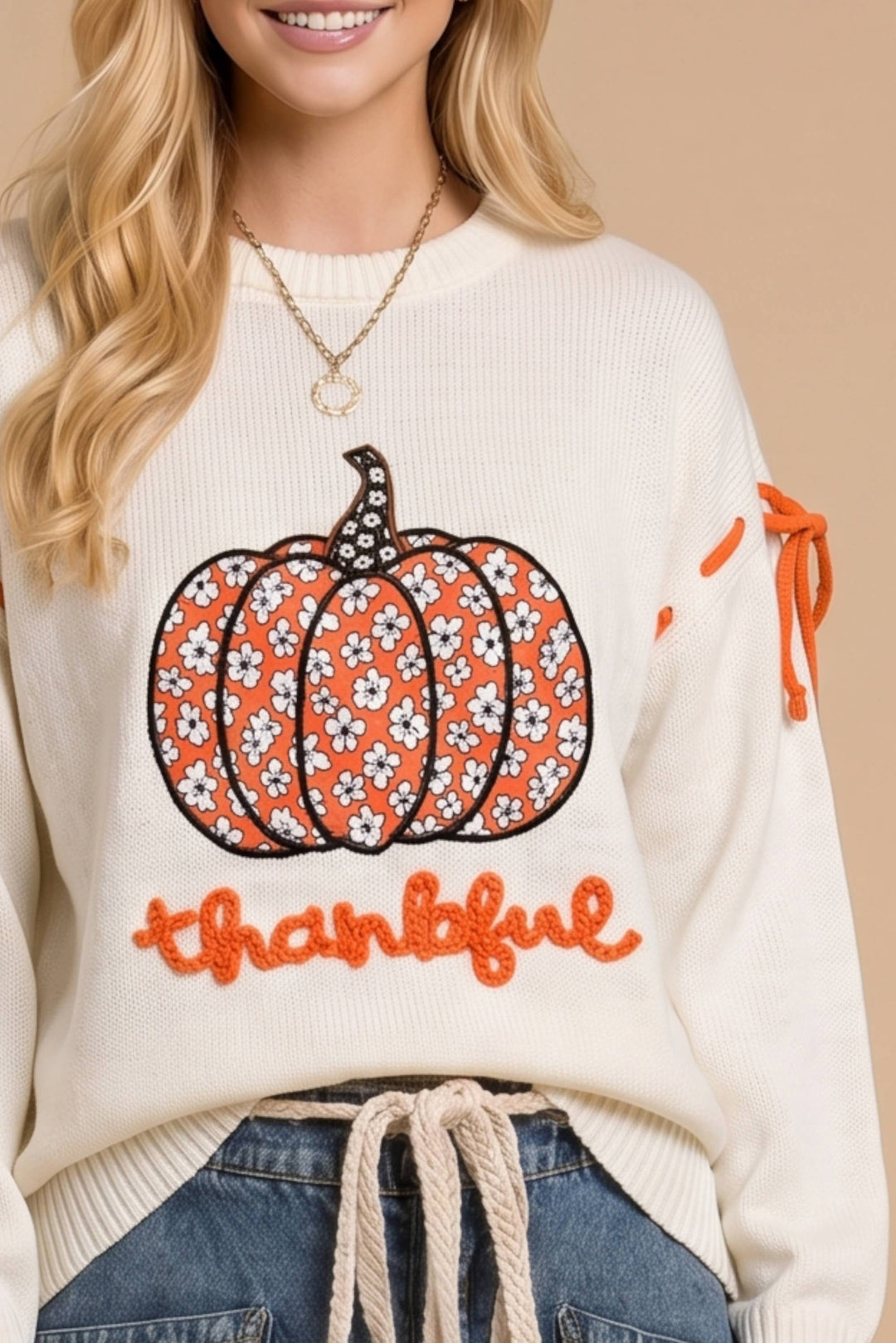 Person wearing a sweater with a pumpkin design and &