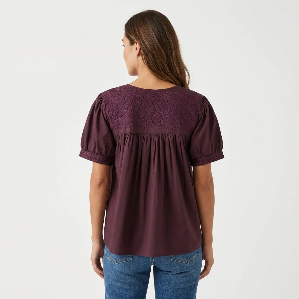Woman showing the back of a maroon blouse.
