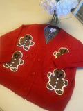 Red sweater with gingerbread man designs on a light-colored surface.