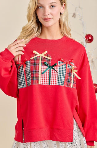 Red sweater with plaid patterns and bows worn by a model against a neutral background